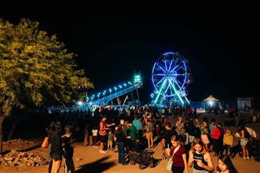 Ferris wheel lit up at night with crowds