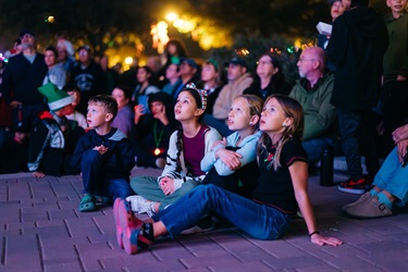 Kids sitting on the ground watching the show at Holiday Festival
