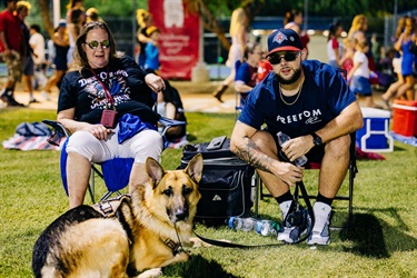 Two attendees pose with dog on the field