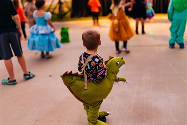 Trick-or-treater on a dinosaur 